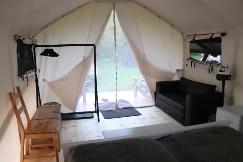 OzolniekiGlempings Kaziņu ferma Līcīši的帐篷内配有沙发和椅子的房间