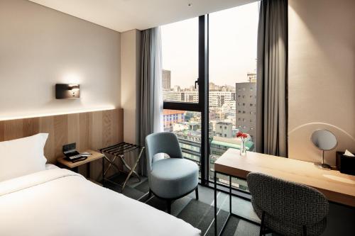首尔G3 Hotel Chungmuro的配有一张床、一张书桌和一扇窗户的酒店客房