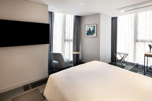 首尔G3 Hotel Chungmuro的配有一张床和一台平面电视的酒店客房