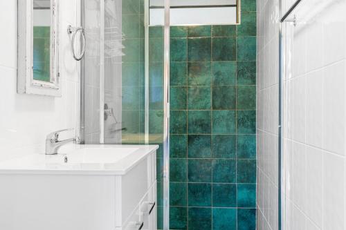 伊鲁卡Pelicans Eleven Iluka Villa 11的浴室设有水槽和绿色瓷砖淋浴。