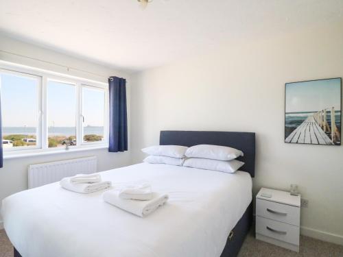 韦茅斯Tidal Drift的卧室配有一张带白色床单和枕头的大床。