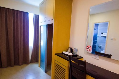 哥打京那巴鲁GRAND EASTERN HOTEL SDN BHD的一间设有黄色墙壁和镜子的客房