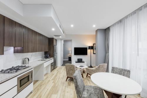 悉尼帕拉马塔教堂街美利通公寓式酒店的厨房以及带桌椅的起居室。