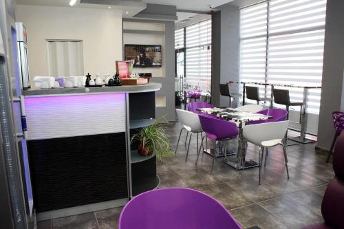 塞夫利耶沃Incanto Family Hotel的一间酒吧,里面配有紫色椅子和一张桌子