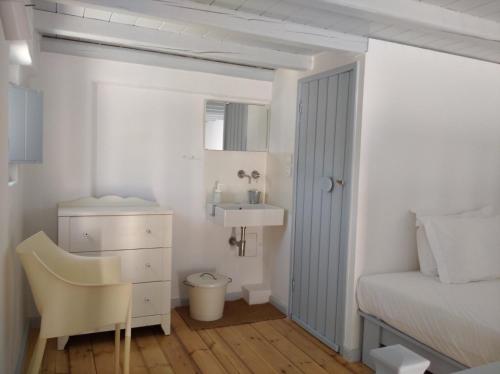 佐努萨岛Theros Apartments Donoussa的一间卧室配有一张床、一张桌子和一把椅子