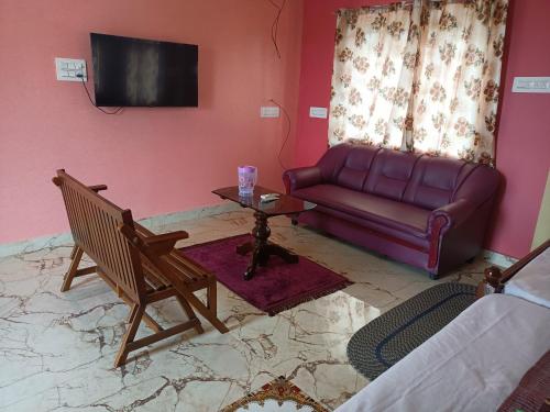 蓬蒂切里Guru Residency Pondicherry的客厅配有沙发和桌子