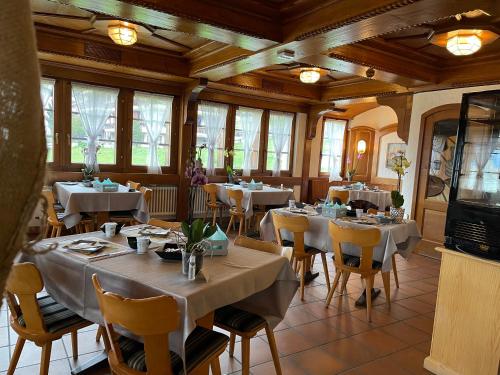 Visperterminen红峰酒店及餐馆的餐厅设有白色的桌椅和窗户。