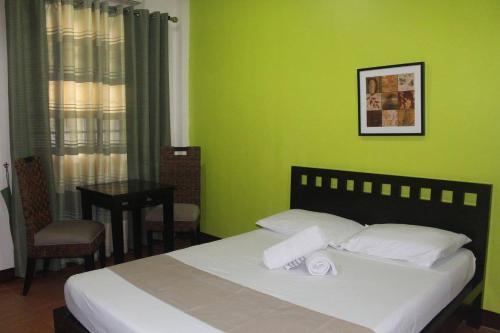安吉利斯CASA DEL ROQUE的一间拥有绿色墙壁的卧室和一张带两条毛巾的床