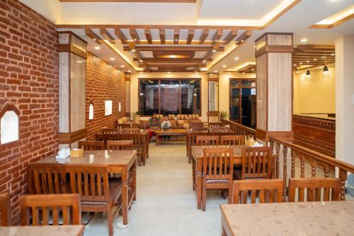 加德满都Madhuban Hotel的餐厅设有木桌和椅子,拥有砖墙