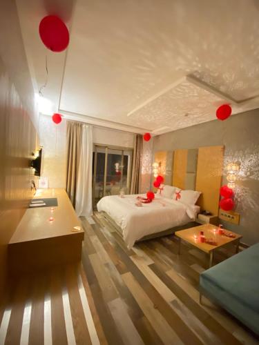 Douar DraoudHotel Atlantis Mazagan的一间卧室配有一张床、一张桌子和红色气球