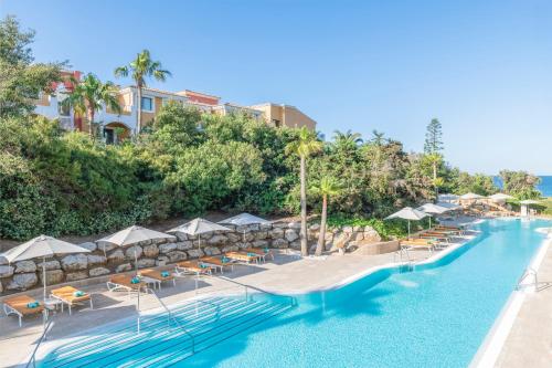 奇克拉纳－德拉弗龙特拉Iberostar Selection Andalucia Playa的度假村的游泳池,配有椅子和遮阳伞