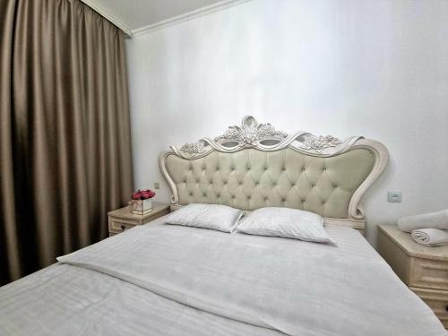 阿拉木图Очень уютная квартира рядом с посольством США的卧室配有白色的床头板和白色的床