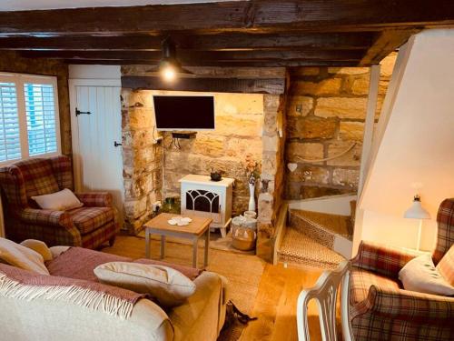 惠特比Cosy 400 yr old Cottage, Flowergate, Whitby的带沙发和石墙的客厅