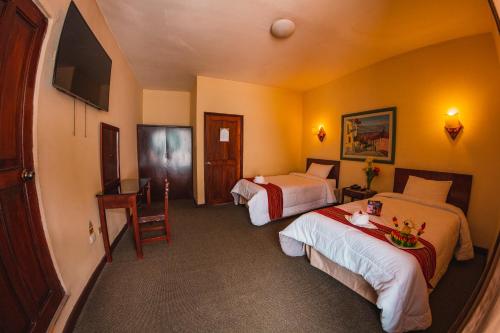 卡哈马卡Hotel Cajamarca的酒店客房配有两张床和一张书桌
