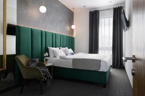 白采尔科维Ribas Rooms Bila Tserkva的一间卧室配有一张带绿色床头板的床和一把椅子