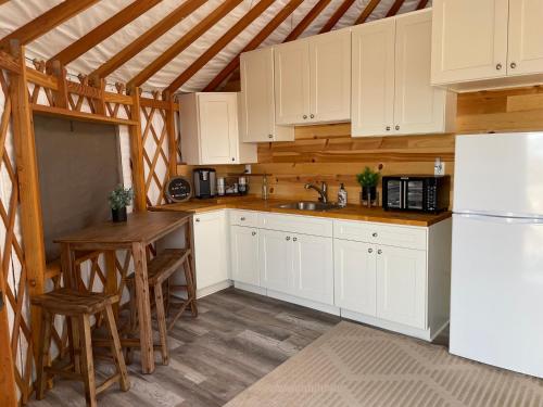 蒂梅丘拉Yurt Escape with Amazing Country Views的厨房配有白色橱柜、桌子和冰箱。