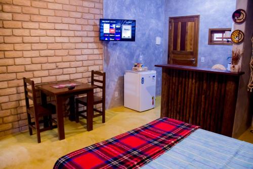 尼泰罗伊Chalé 01 Itaipu Vale da Colina Niterói的客房设有床、桌子和小厨房。