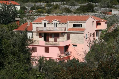 拉茨斯切Apartments by the sea Racisce, Korcula - 4359的山丘上种有树木的粉红色房子