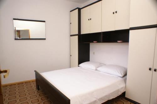 普利兹巴Apartments by the sea Grscica, Korcula - 4487的一间卧室配有一张床、白色橱柜和镜子