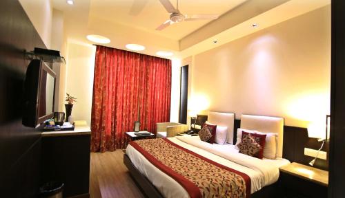新德里新德里火车站普莱姆巴拉吉豪华酒店的酒店客房,配有床和红色窗帘