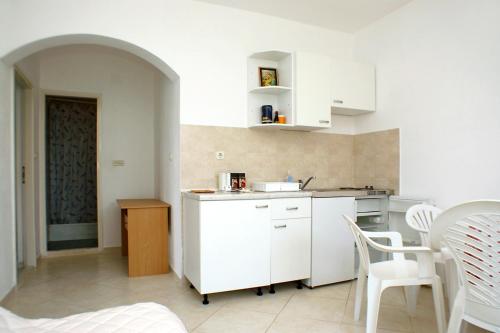 赞吉纳Apartments by the sea Luka Dubrava, Peljesac - 4568的厨房配有白色橱柜和桌椅