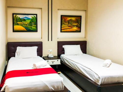 帕卢RedDoorz At Hotel Gajah Mada Palu的墙上画作的房间里设有两张床