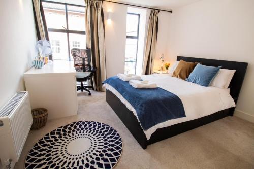 牛津The New52 Oxford by 360Stays - Bespoke 2 Bed Luxury Apartment in the Heart of Oxford City Center with Parking的一间卧室配有一张床、一张书桌和一个窗户。