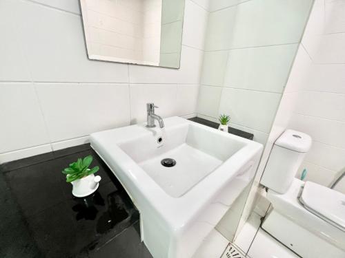 实达阿南A 1-4 pax Cozy Studio TV Box Pool 100mps Wifi 3 bed Trefoil Setia Alam的白色的浴室设有水槽和卫生间。