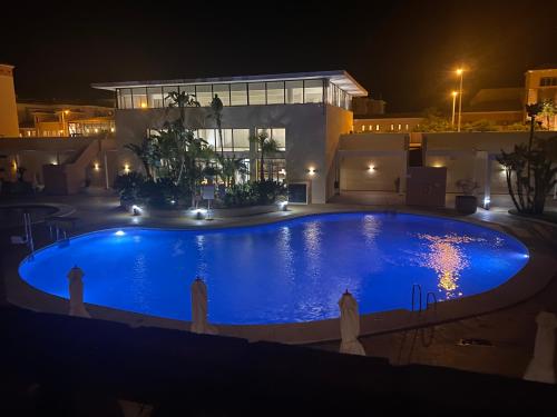 蓬塔翁布里亚Apartamento Punta Umbría Parking Incluido y Piscina的一座大型游泳池,在晚上在房子前面