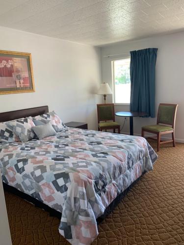 蒙蒂塞洛Monticello Inn - Monticello, Indiana的一间卧室配有一张床、两把椅子和一个窗户