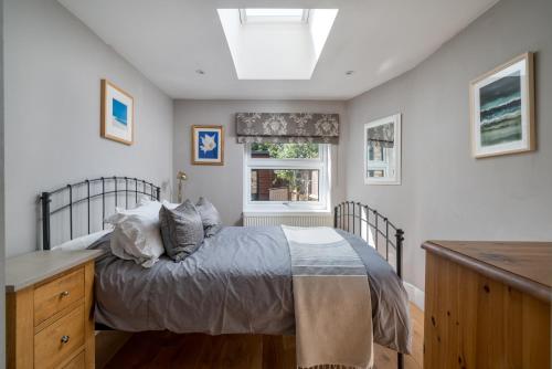 伦敦JOIVY 2-bed flat with garden in Battersea的一间卧室配有一张床、一张书桌和一个窗户。