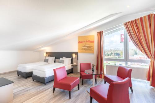 施图尔Select Hotel A1 Bremen-Stuhr的酒店客房,配有床铺和红色椅子