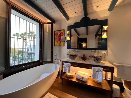 埃尔罗西奥Hotel La Malvasía的一间带大浴缸和大窗户的浴室