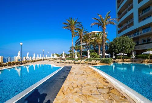 梅利哈马耳他金沙滩丽笙度假及spa酒店的棕榈树和建筑度假村的游泳池