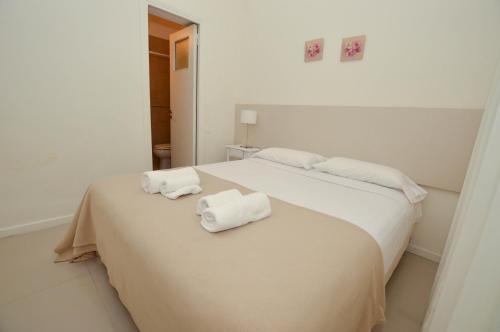 马德普拉塔Hotel Acqua的一间白色卧室,床上配有2条毛巾