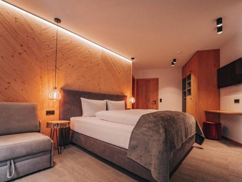 圣安东阿尔贝格ARLhome - Zuhause am Arlberg的一间卧室配有一张大床和一把椅子