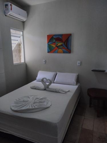 马拉戈日Mandala Hostel Maragogi Oficial的卧室内的一张床铺,墙上有绘画作品
