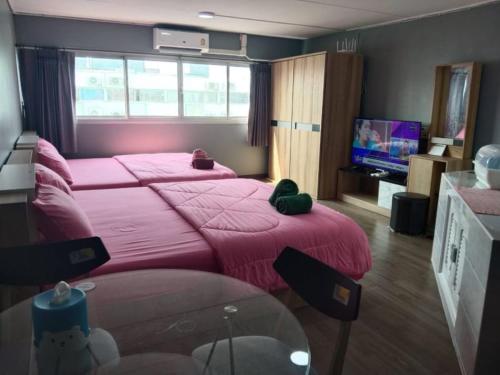 暖武里府K.NAT Room service的一间卧室配有两张带粉色床单的床和电视。