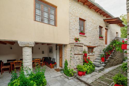 莫诺登德里Archontiko Rapti Stone Traditional House的石头建筑,设有配有桌椅的庭院