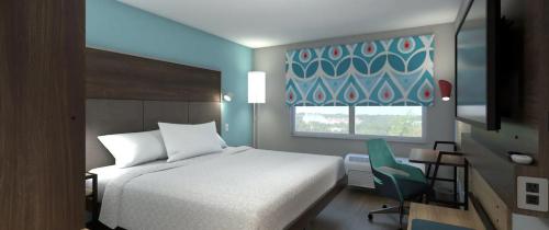 曼特卡Tru By Hilton Manteca的卧室配有床、椅子和窗户。