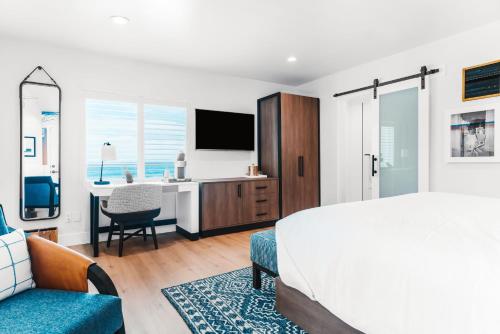 圣地亚哥Del Mar Beach Hotel的一间卧室配有一张床和一张书桌及电视