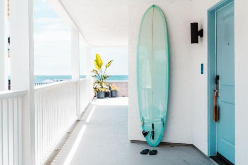 圣地亚哥Del Mar Beach Hotel的靠在门边墙上的冲浪板