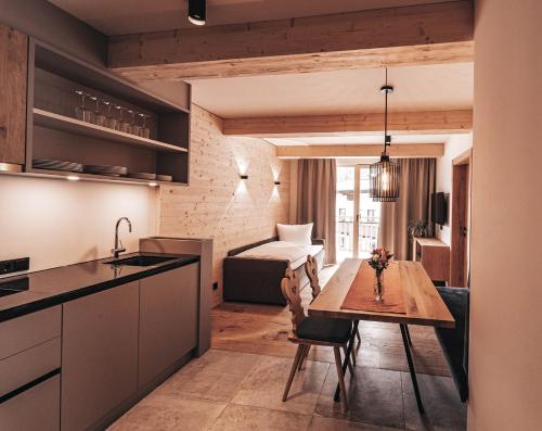 圣安东阿尔贝格ARLhome - Zuhause am Arlberg的一间厨房、一间带桌子的用餐室和一间带床的房间