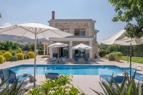阿尔加卡Rafaella Beach Villa- Pvt Pool-Near Sea/Beach的一个带遮阳伞和椅子的游泳池以及一座房子
