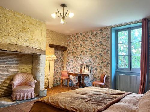 蒙蒂尼亚克Le Clos Chalmon Chambre d'hôte的一间卧室配有一张床、一个壁炉和一张书桌