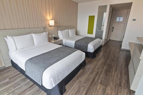 伊瓦格Sonesta Hotel Ibagué的配有2张床的酒店客房,铺有木地板