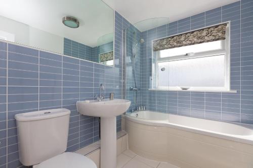卡比斯贝Atlantic Blue的蓝色瓷砖浴室设有卫生间和水槽
