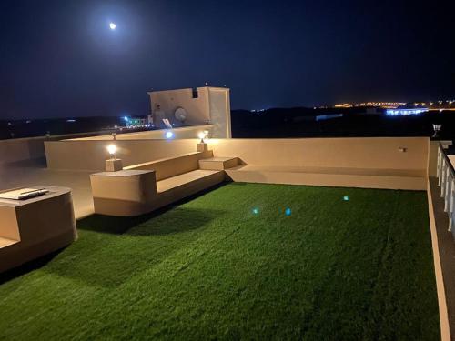 塞拉莱Almouj Chalet的夜晚在房子屋顶上的绿色草坪