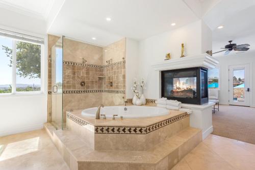蒂梅丘拉Gaia Inn & Spa- Adults Only- Temecula Wine Country的带浴缸的大型浴室和电视。