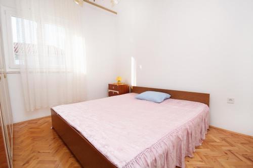 苏佩塔尔Apartments with a parking space Supetar, Brac - 6035的一间卧室配有一张带白色床单的床和一扇窗户。